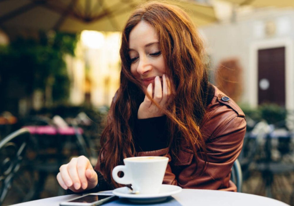 Illustrasjonsfoto: Dame på cafe med kaffekopp og mobiltelefon