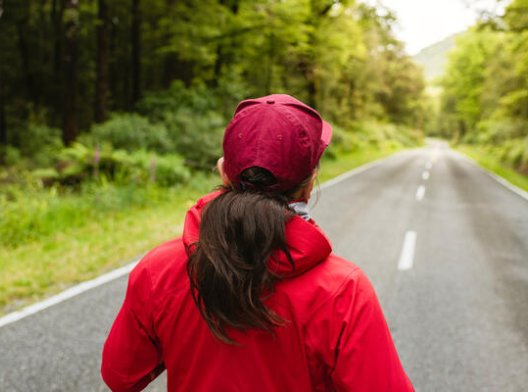 Kvinne som jogger på en asfaltert vei Kvinne som jogger på en asfaltert vei